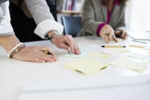 Midsection of businesswomen preparing reminders at desk in office