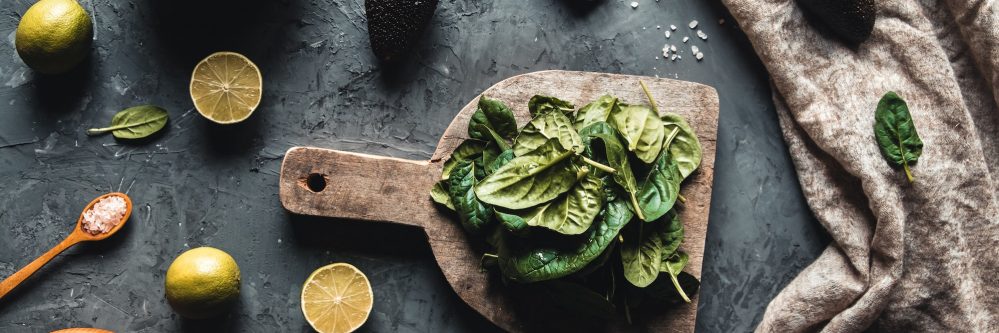 Healthy foods, cooking and vegetarian concept spinach leaves, lemon, apples, avocado, cutting board