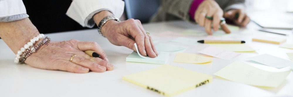 Midsection of businesswomen preparing reminders at desk in office